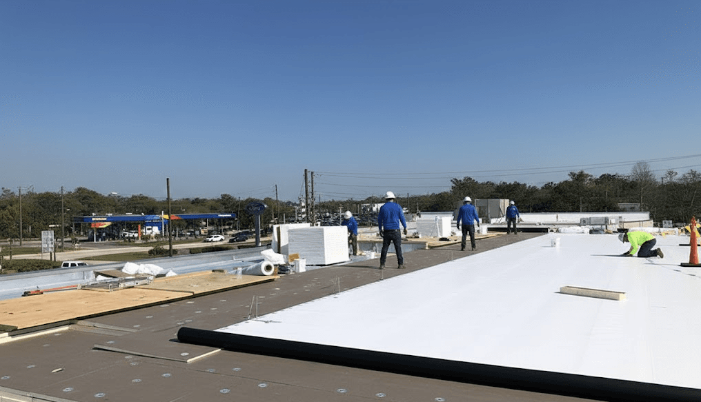 Commercial roofing crew installing flat roof membrane